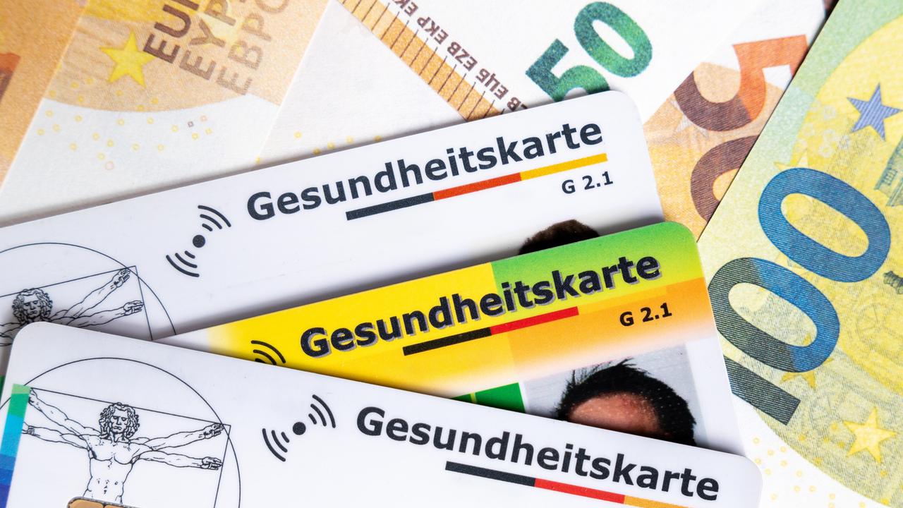 Mehrere Gesundheitskarten liegen auf Euroscheinen. Das Bild symbolisiert steigende Krankenkassenbeiträge, hohe Gesundheitskosten und die politische Debatte um die Finanzierung des Gesundheitssystems. Mehrere Gesundheitskarten liegen auf Euroscheinen. Das Bild symbolisiert steigende Krankenkassenbeiträge, hohe Gesundheitskosten und die politische Debatte um die Finanzierung des Gesundheitssystems.