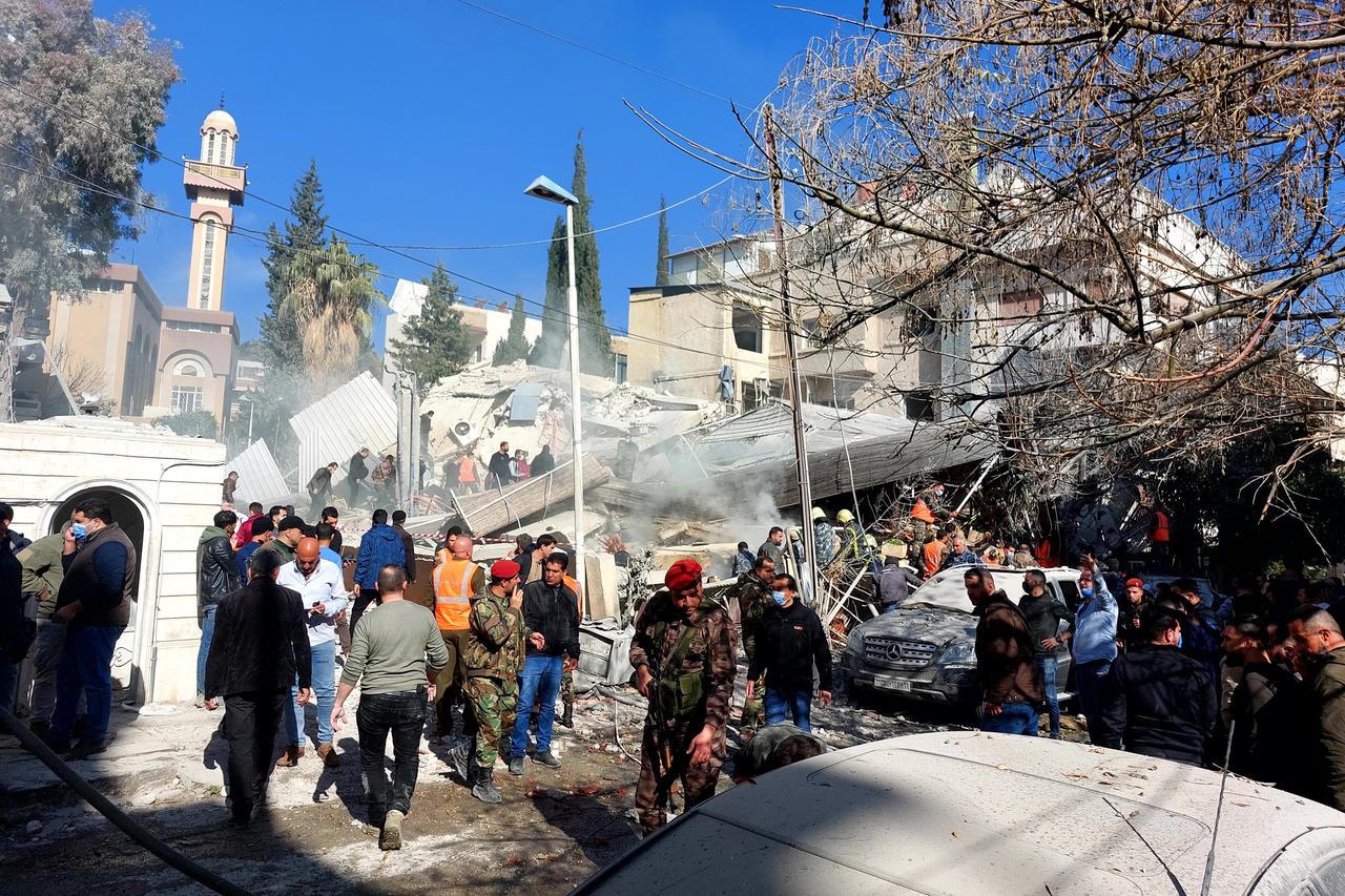 Menschen versammeln sich vor den Trümmern eines eingestürzten Gebäudes.