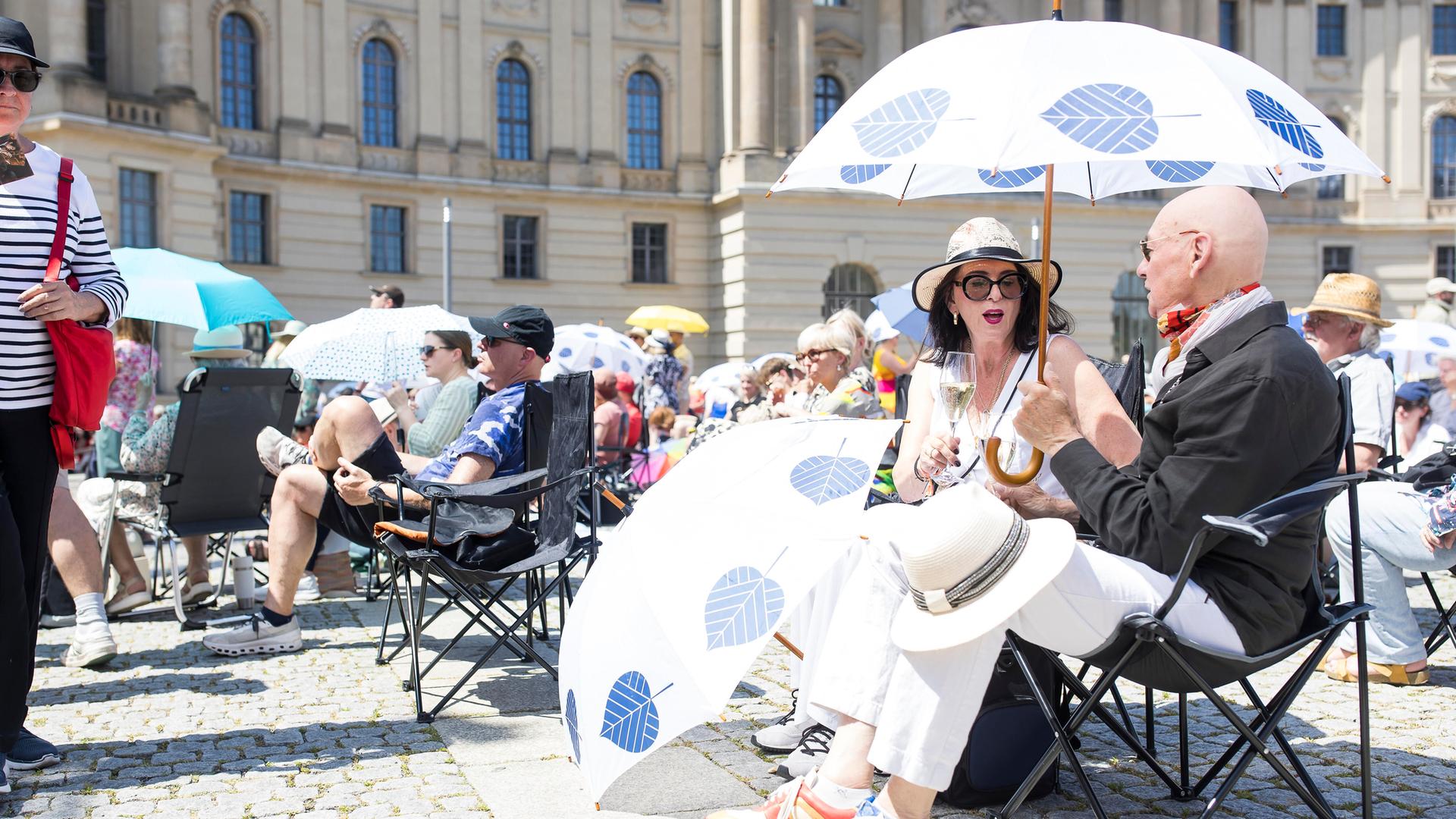Zwei Besucher unter einem Schirm bei der Staatsoper für alle auf dem Bebelplatz in Berlin. Zwei Besucher unter einem Schirm bei der Staatsoper für alle auf dem Bebelplatz in Berlin.