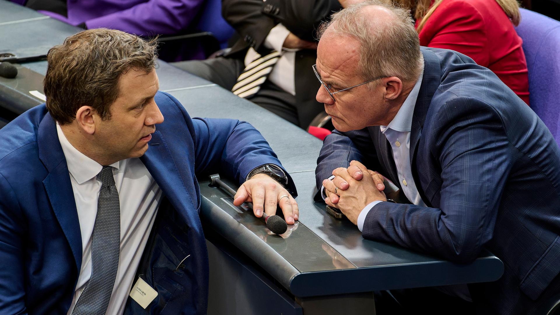 Klingbeil und Miersch im Gespräch. Sie sitzen sich im Bundestag gegenüber und schauen einander an.