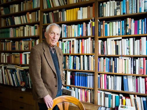 Dieter Wellershoff steht in seiner Wohnung vor einem wandfüllendem Bücherregal.