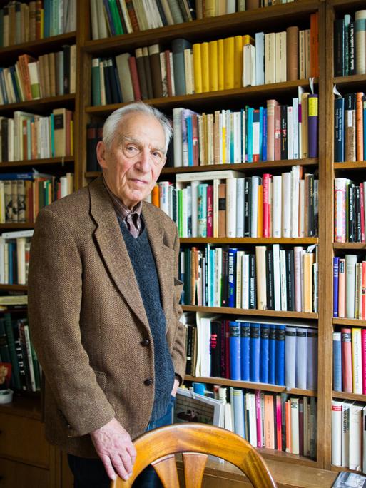 Dieter Wellershoff steht in seiner Wohnung vor einem wandfüllendem Bücherregal.