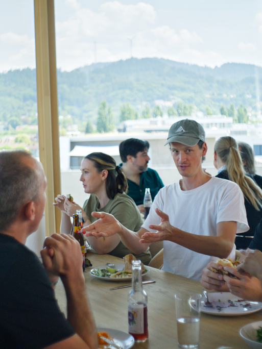 Mitarbeiter des Freiburger Startups Black Forest Labs sitzen an einem Esstisch in einer Kantine. Durch große Fenster sind im Hintergrund die Hügel des Schwarzwald zu sehen. Mitarbeiter des Freiburger Startups Black Forest Labs sitzen an einem Esstisch in einer Kantine. Durch große Fenster sind im Hintergrund die Hügel des Schwarzwald zu sehen.