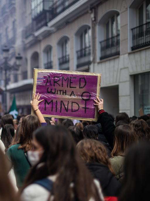 Bei einer feministischen Demonstration ist ein Plakat mit der Aufschrift "Armed With A Mind" zu sehen.