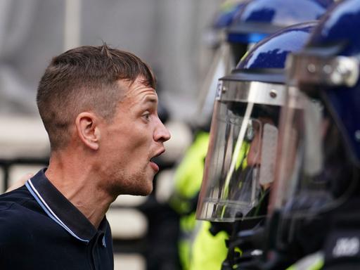 Konfrontative Szene zwischen einem Demonstranten und einem Polizeibeamten bei Protesten im Sommer 2024 in London