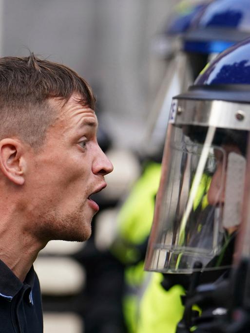 Konfrontative Szene zwischen einem Demonstranten und einem Polizeibeamten bei Protesten im Sommer 2024 in London