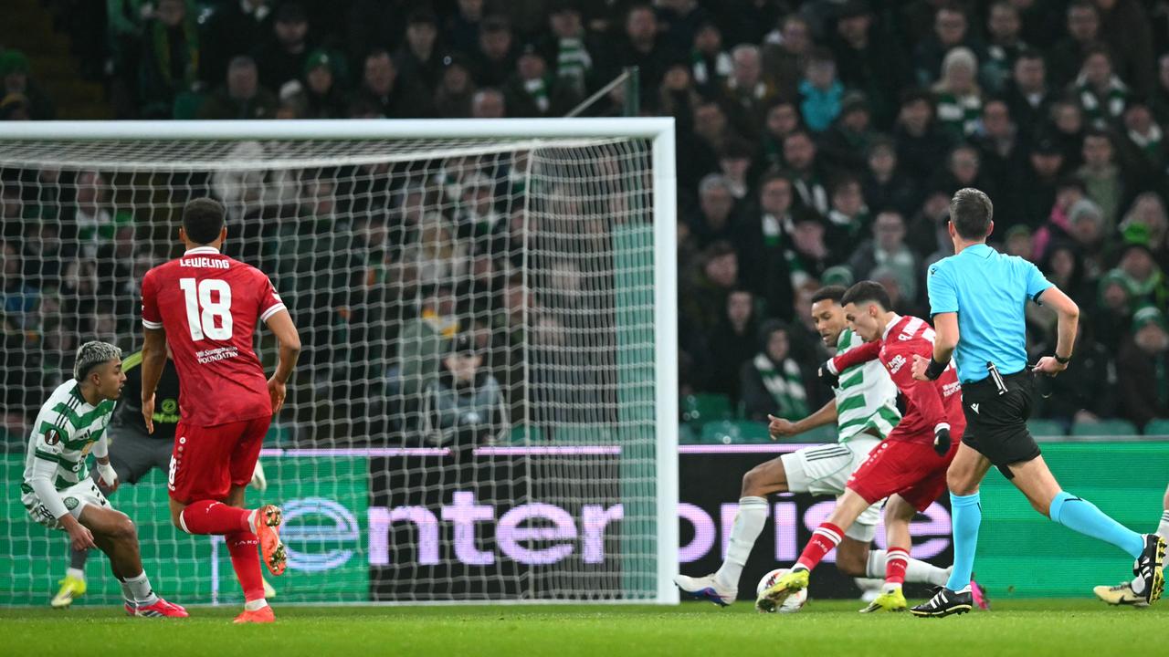 Ein Fußballspieler setzt sich gegen seine Gegenspieler durch und schießt aufs Tor.