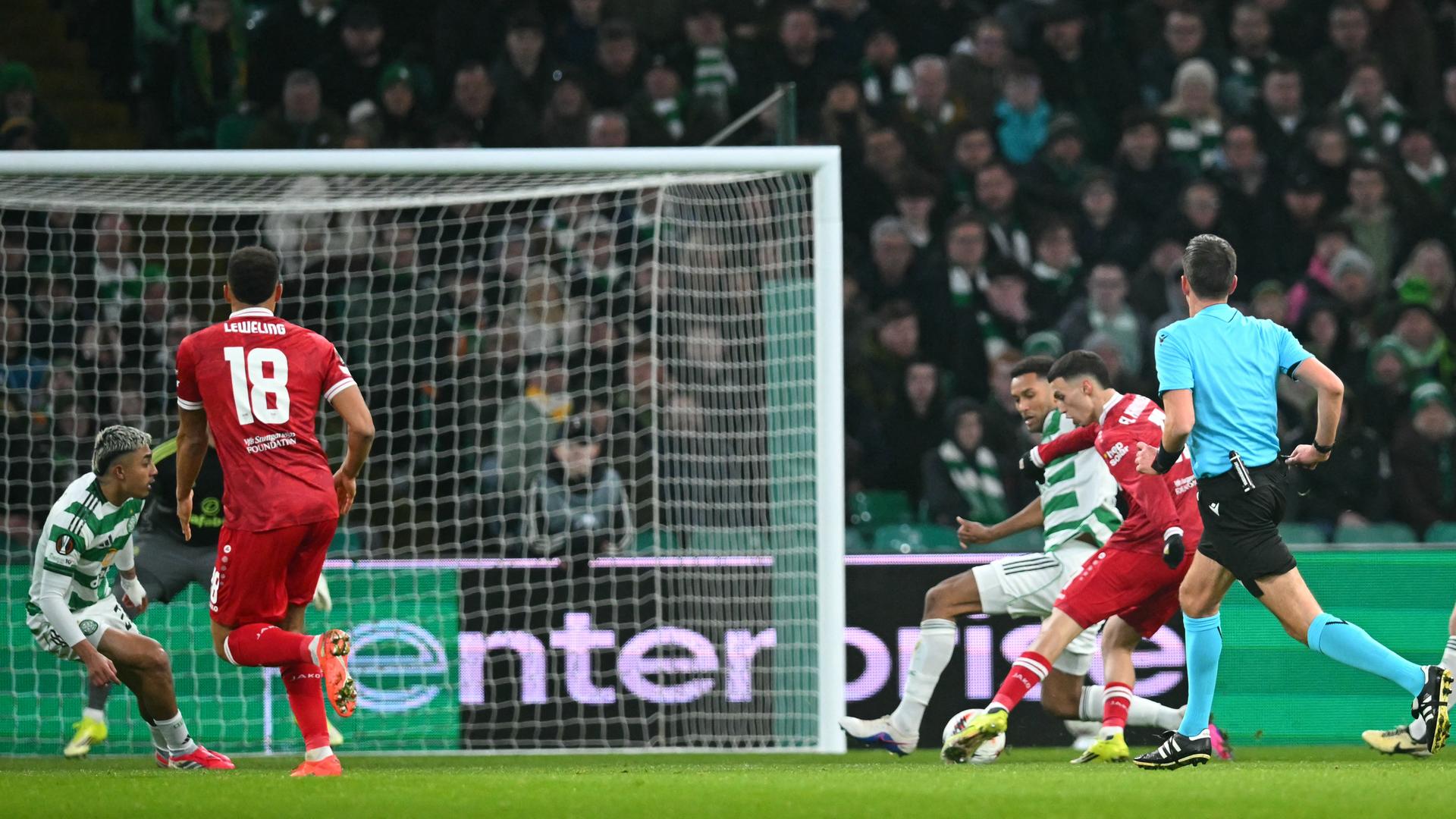 Ein Fußballspieler setzt sich gegen seine Gegenspieler durch und schießt aufs Tor.