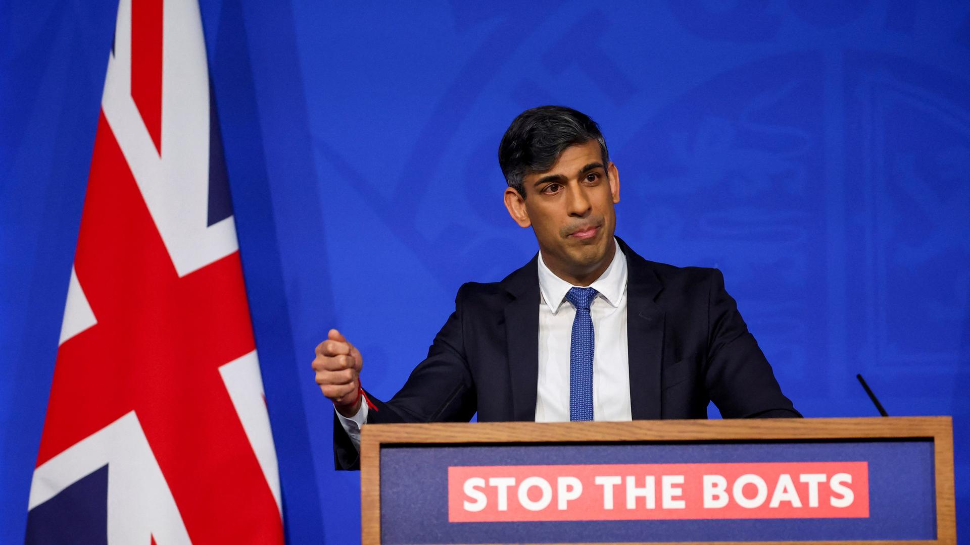 Sunak steht bei einer Pressekonferenz hinter einem Rednerpult. Im Hintergrund ist die britische Flagge zu sehen.
