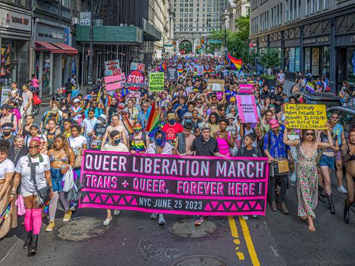 Eine Demonstration für queeres Leben im Juni 2023 in New York City. Die Protestierenden tragen Transparente und viele Farben der queeren Bewegung.