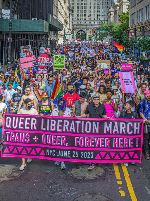 Eine Demonstration für queeres Leben im Juni 2023 in New York City. Die Protestierenden tragen Transparente und viele Farben der queeren Bewegung.