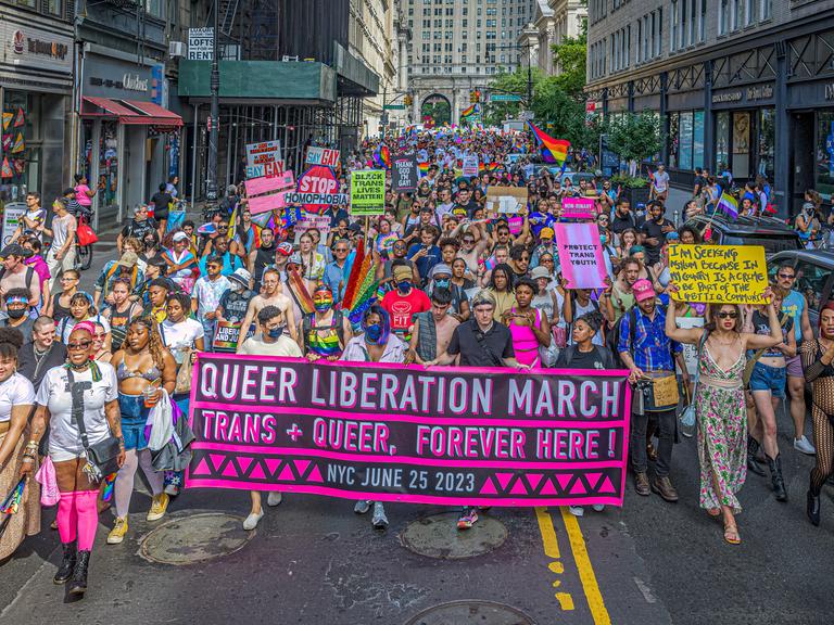 Eine Demonstration für queeres Leben im Juni 2023 in New York City. Die Protestierenden tragen Transparente und viele Farben der queeren Bewegung.