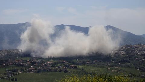 Nach Explosionen steigen in einer hügeligen Landschaft auf. 