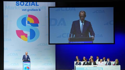 Bundeskanzler Merz steht auf einer Bühne und spricht bei der 41. Bundestagung der Christlich-Demokratische Arbeitnehmerschaft (CDA) in Marburg. Im Hintergrund wird seine Rede auf einer großen Leinwand übertragen.