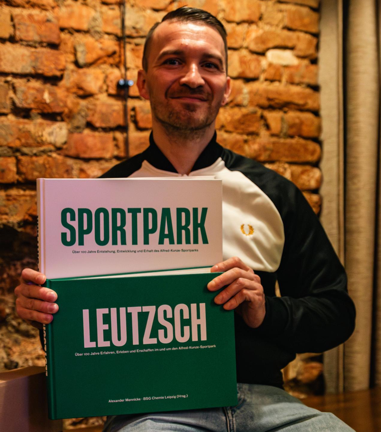 Alexander Mennicke mit den beiden Büchern über den Alfred-Kunze-Sportpark in Leipzig