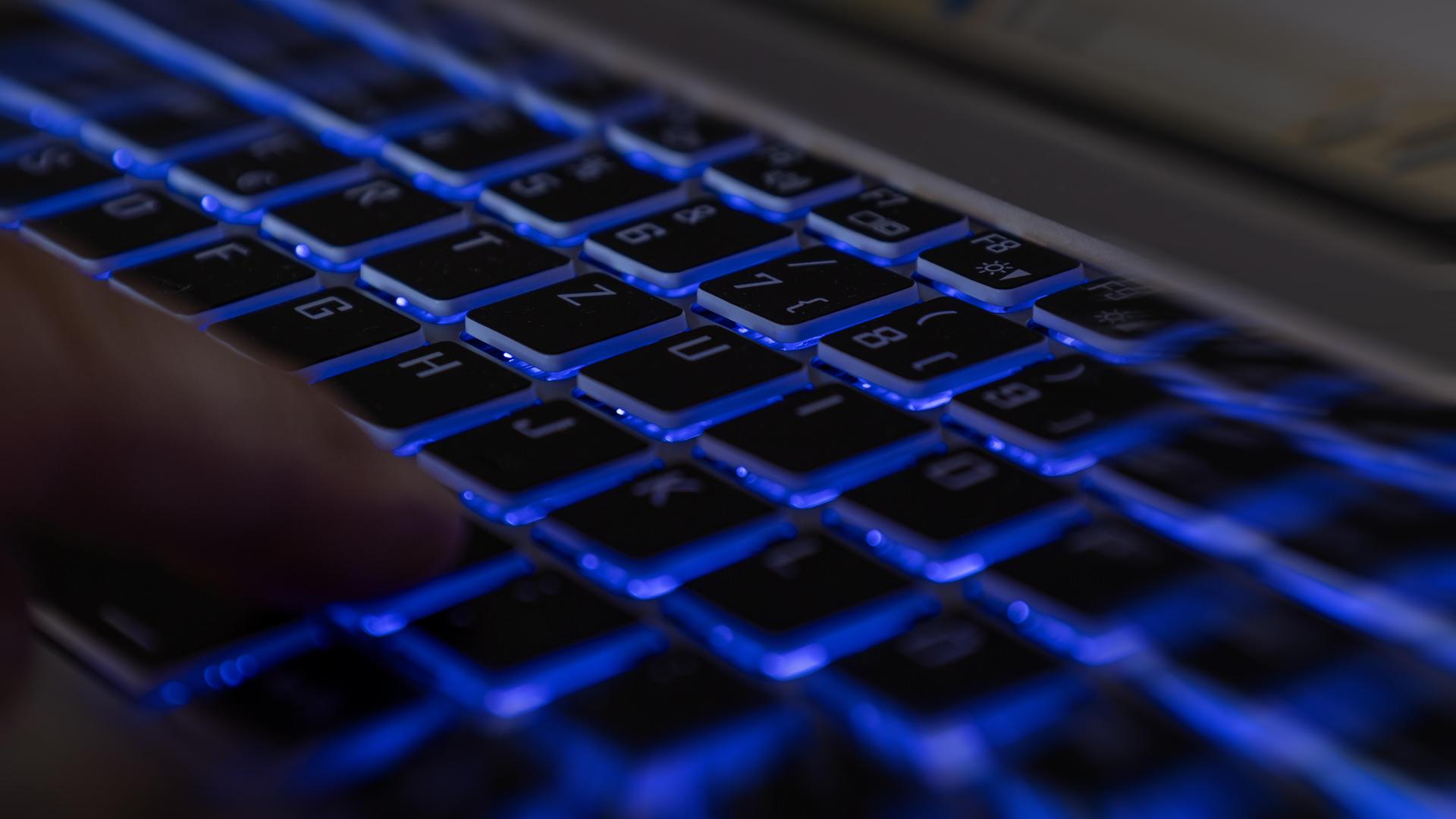 Ein Finger auf der Tastatur eines Laptops in dunkler Umgebung als Symbolbild für einen Hackerangriff. 