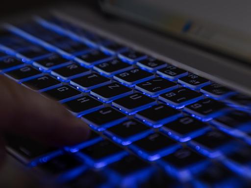 Ein Finger auf der Tastatur eines Laptops in dunkler Umgebung als Symbolbild für einen Hackerangriff. 