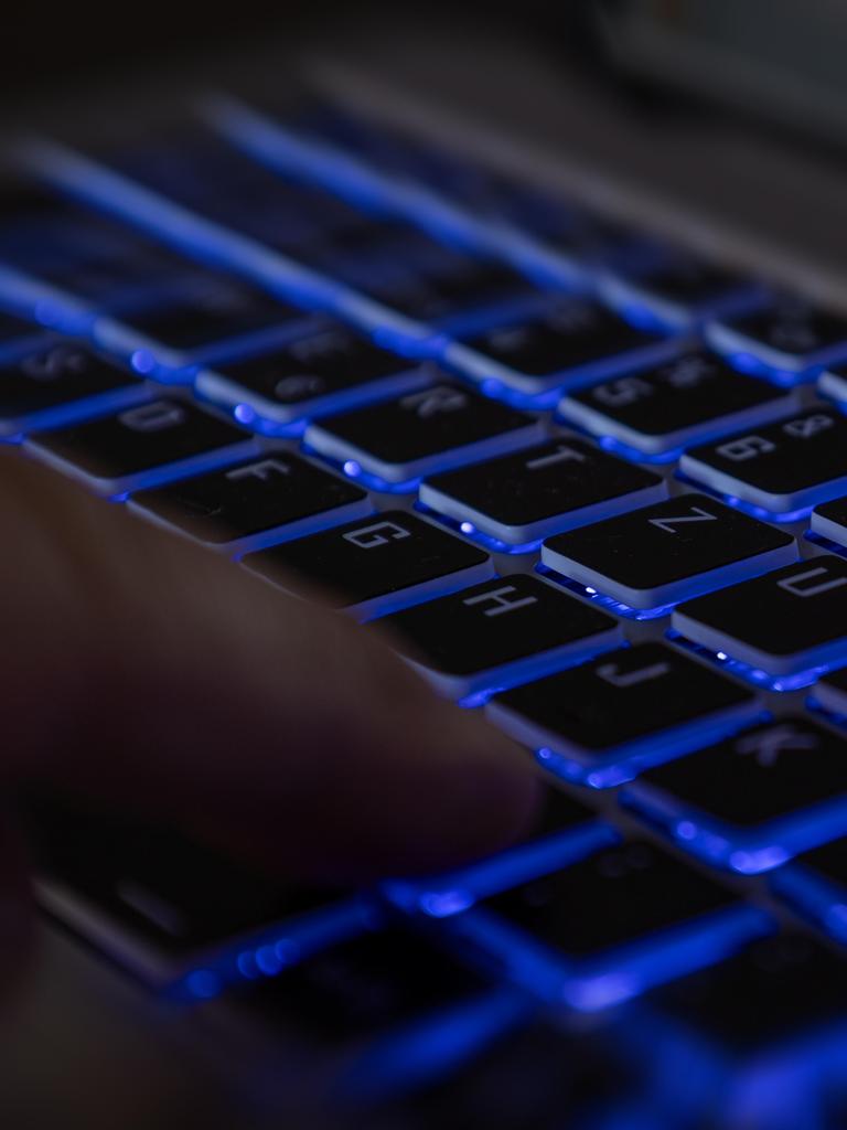 Ein Finger auf der Tastatur eines Laptops in dunkler Umgebung als Symbolbild für einen Hackerangriff. 