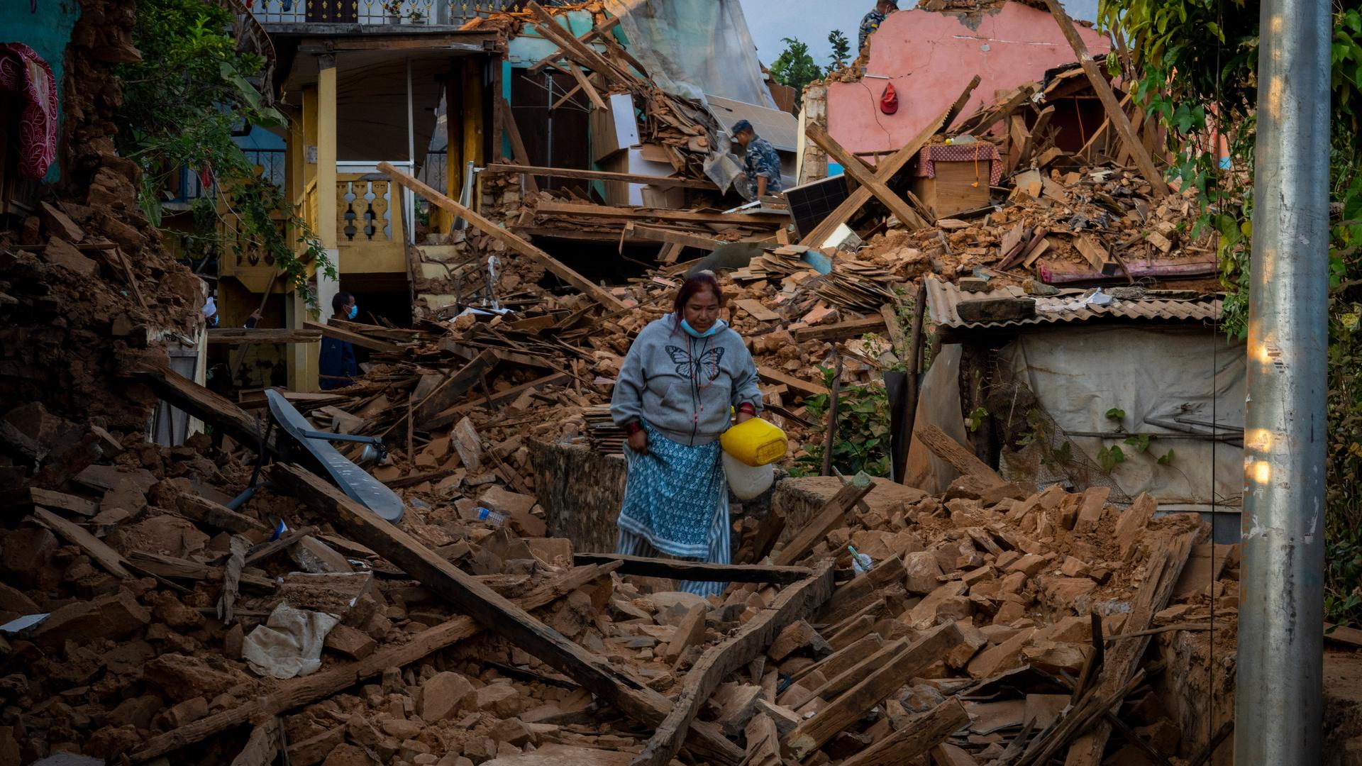 Eine Frau geht an erdbebengeschädigten Häusern im Nordwesten Nepals vorbei.