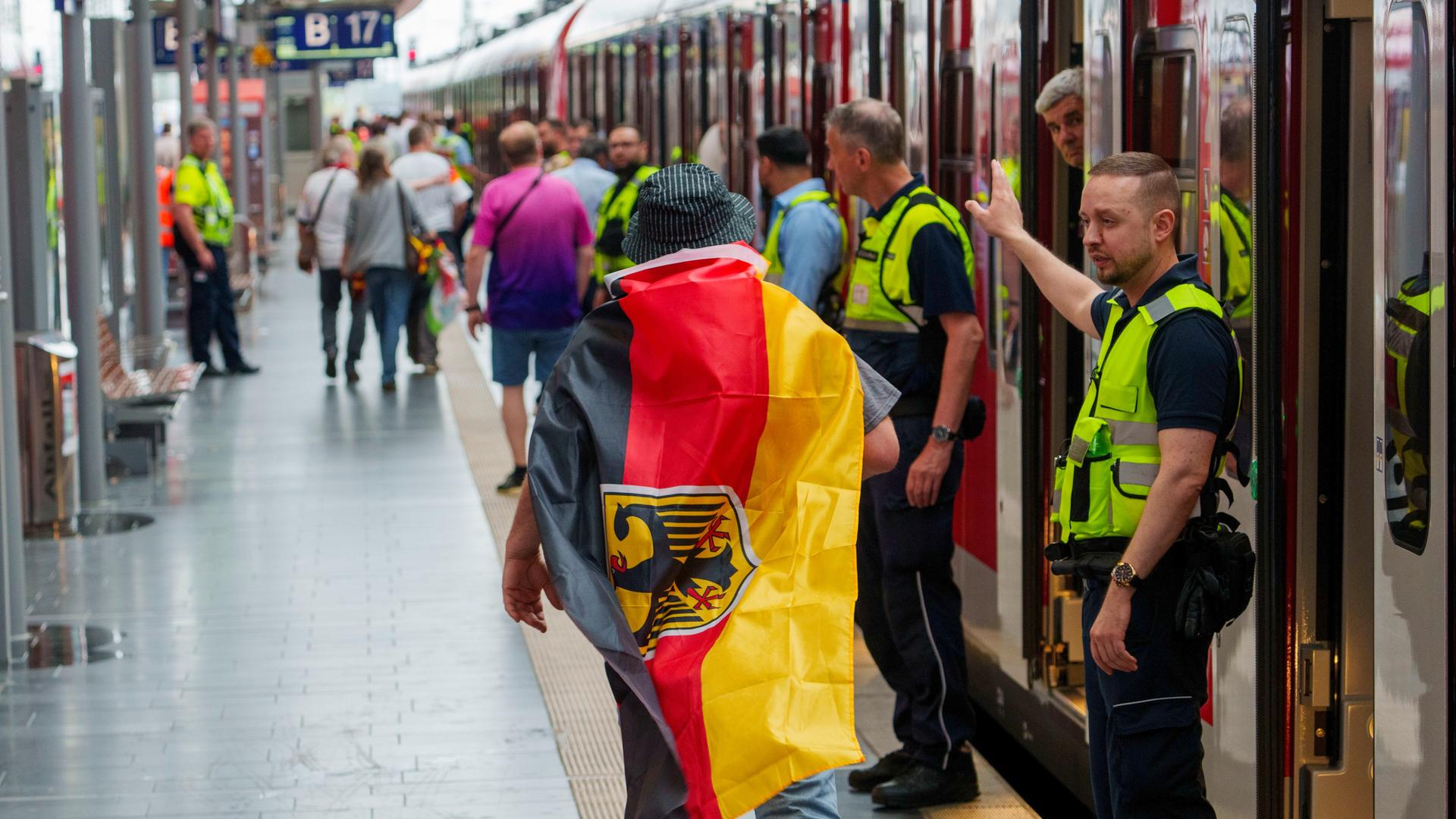 Sicherheitspersonal der Bahn weist einem deutschen Fan den Weg zu einem freien Abteil, ganz am Ende des Zuges. 