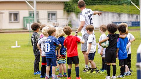 Ein Fußballtrainer leitet ein Kindertraining (Symbolbild)