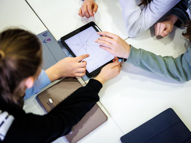 Schülerinnen einer siebten Klasse arbeiten in einem Klassenraum in einer Unterrichtsstunde im Fach Mathe gemeinsam an einem Tablet.  Schülerinnen einer siebten Klasse arbeiten in einem Klassenraum in einer Unterrichtsstunde im Fach Mathe gemeinsam an einem Tablet.