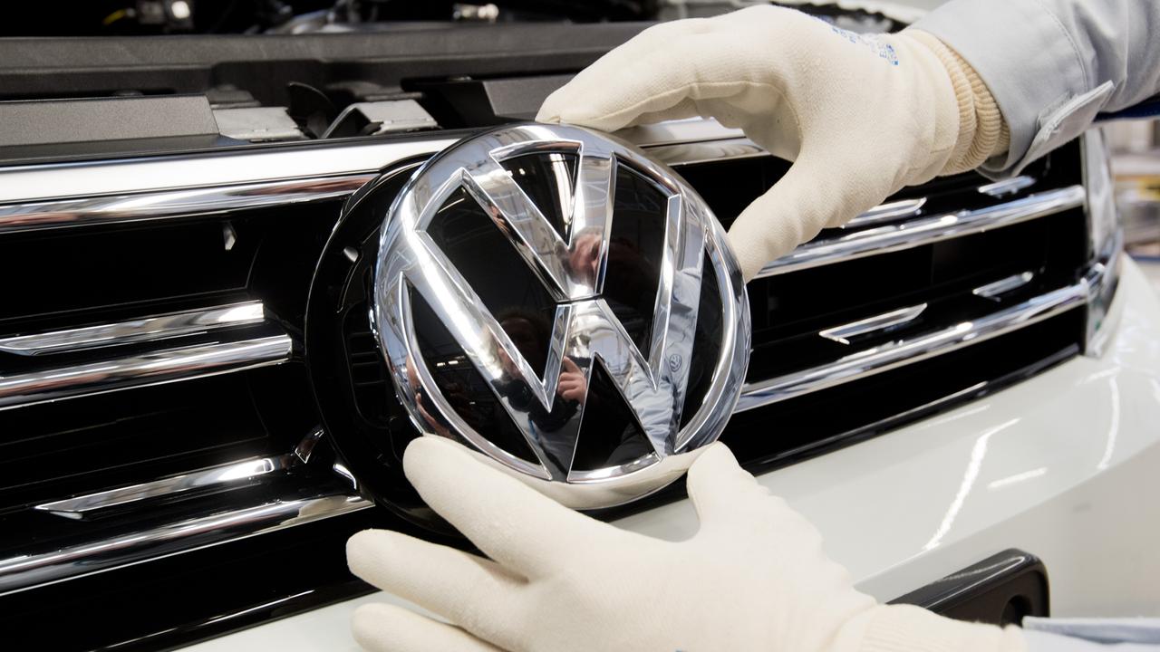 Ein Mitarbeiter montiert ein VW Logo an die Front eines VW Tiguan 