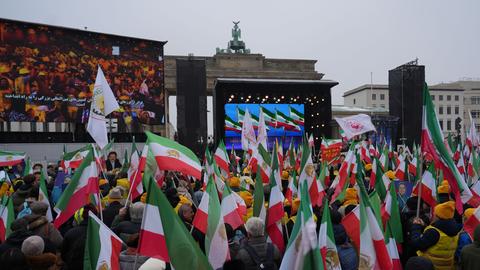 Demonstranten mit Plakaten und Transparenten am Brandenburger Tor in Berlin. 