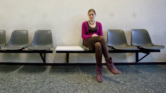 Eine Frau sitzt in einem Warte-Bereich. 