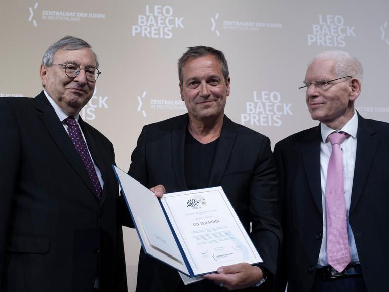 Zu sehen sind links Abraham Lehrer, Vizepräsident des Zentralrats der Juden in Deutschland, in der Mitte Dieter Nuhr mit der Auszeichnung in den Händen und rechts Josef Schuster, Präsident des Zentralrats der Juden in Deutschland. 