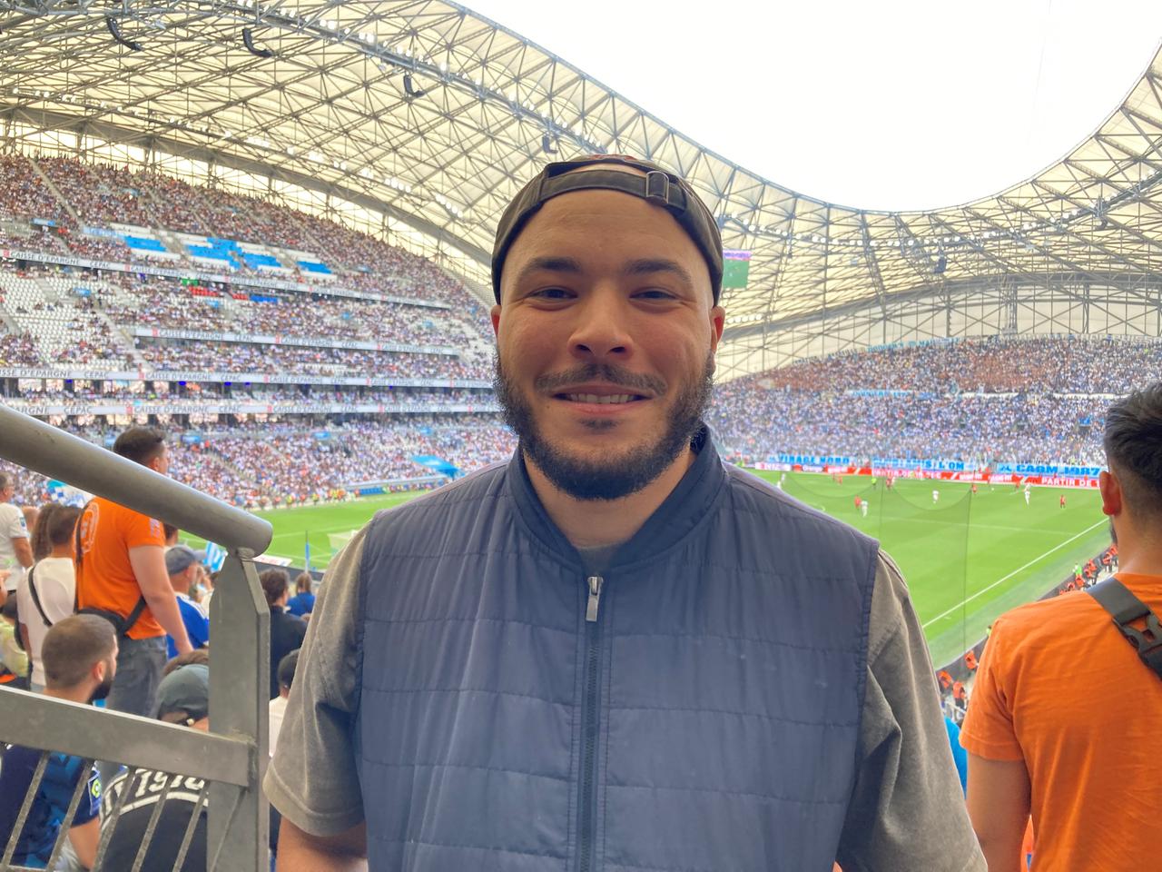 Eine Porträtaufnahme des kanadisch-algerische Journalist Maher Mezahi. Er steht im Stadion von Olympique Marseille, dem Stade Vélodrome.