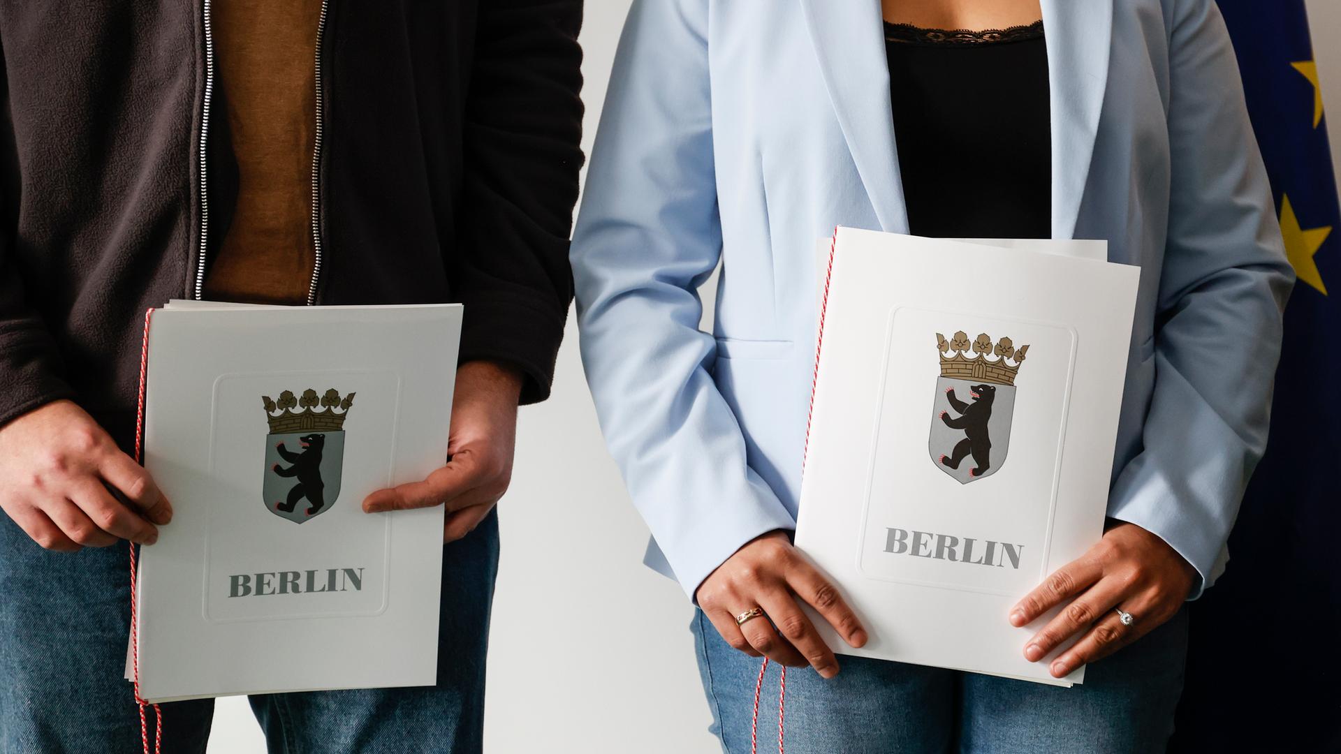 - Eingebürgerte zeigen ihre Einbürgerungsurkunden nach einer Einbürgerungsfeier bei der Zentralen Einbürgerungsstelle des Landesamtes für Einwanderung.