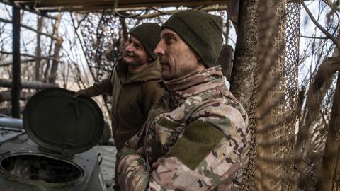 Ukrainische Soldaten in der Region Charkiw bereiten sich auf ein Gefecht vor. Sie tragen Tarnanzüge und Wollmützen. 