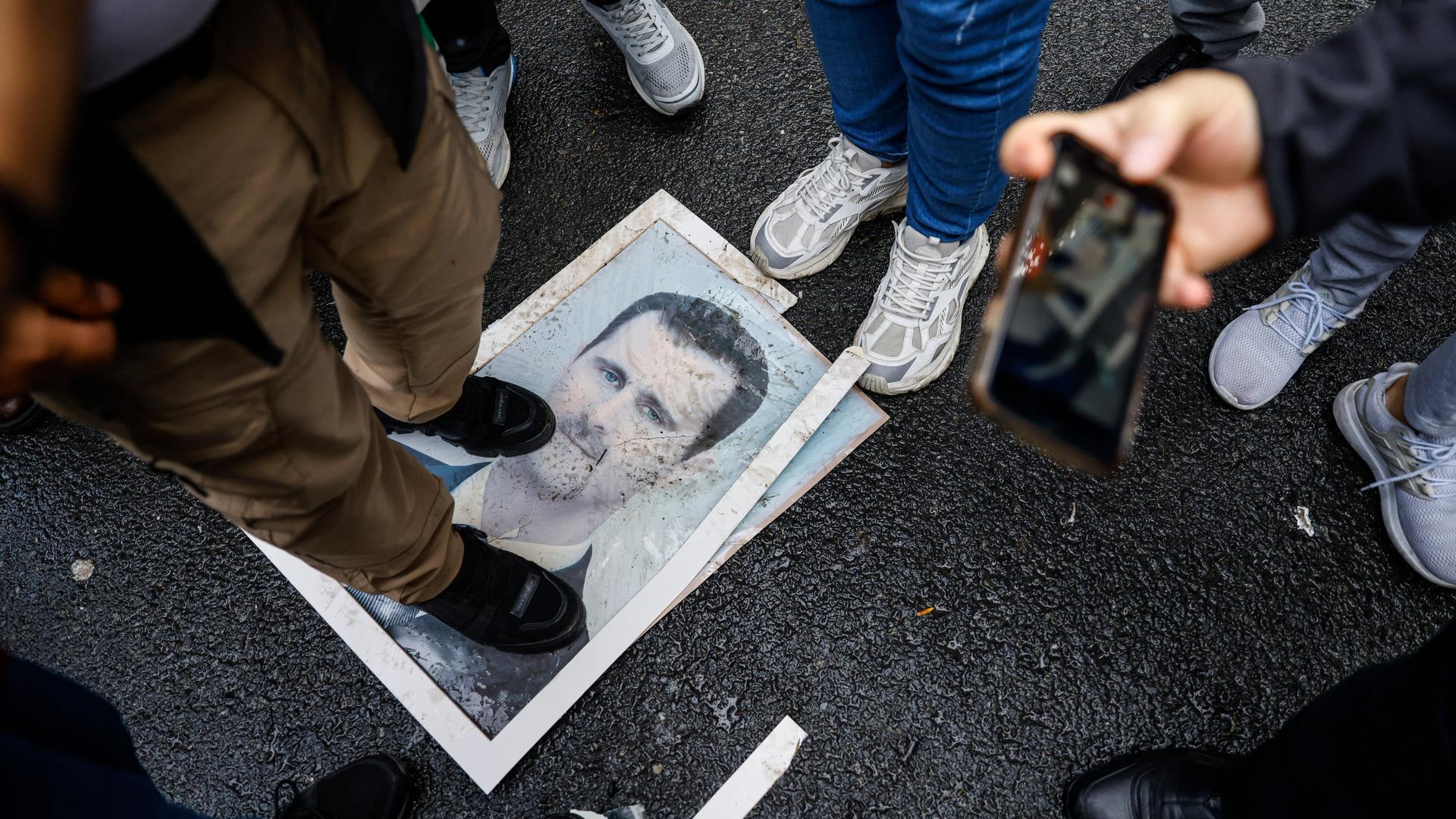 Ein Bild des gestürzten syrischen Machthabers Assad liegt in Istanbul auf dem Boden. Eine Person steht mit ihren Schuhen darauf.