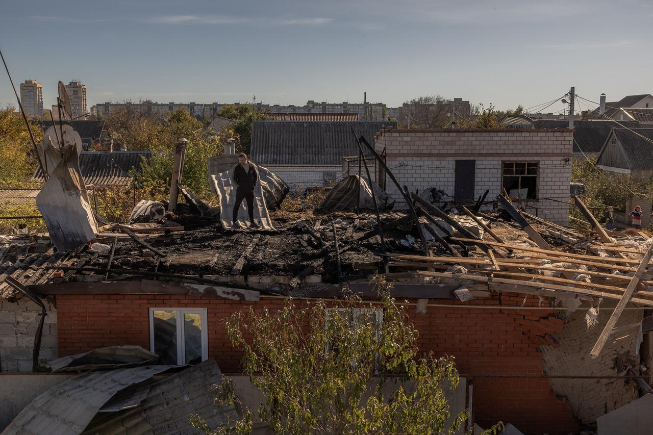 Ein Mann steht in der südukrainischen Stadt Cherson auf einem Hausdach, das während eines russischen Angriffs beschädigt wurde (30. Oktober 2023).