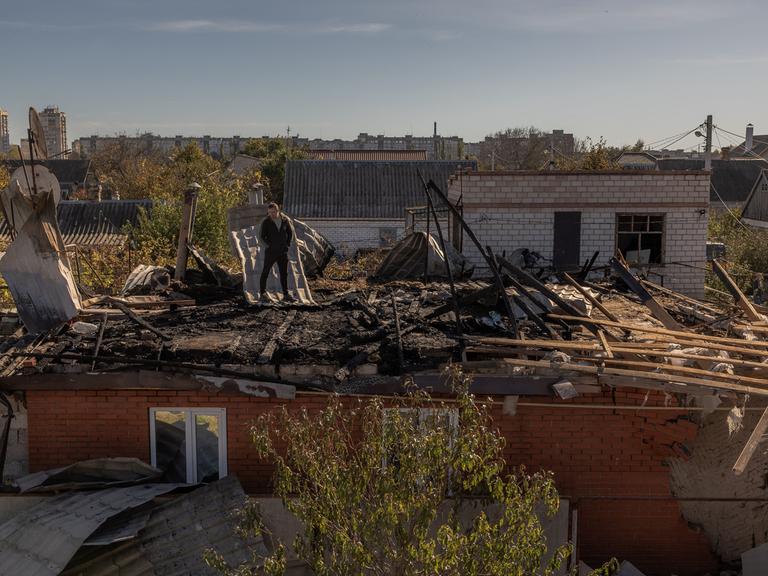 Ein Mann steht in der südukrainischen Stadt Cherson auf einem Hausdach, das während eines russischen Angriffs beschädigt wurde (30. Oktober 2023).