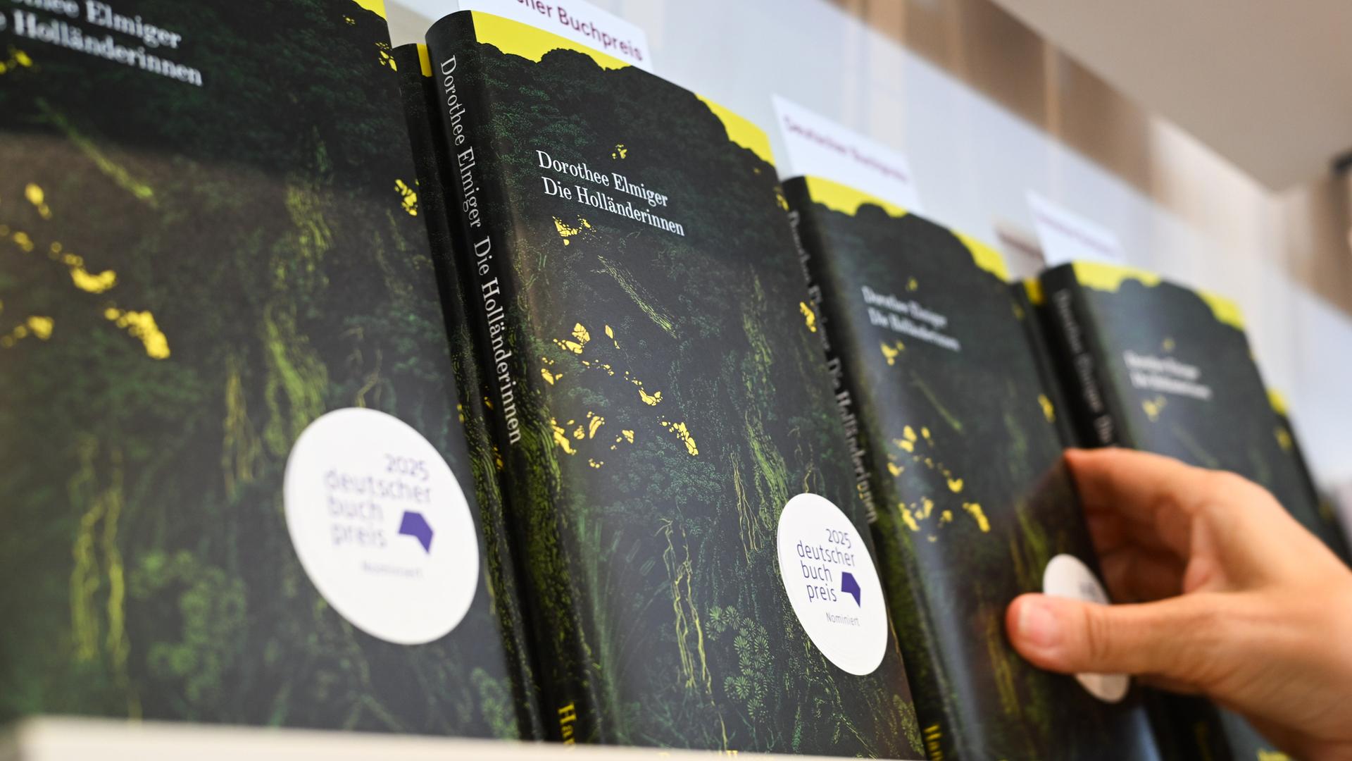 Eine Hand greift am Stand auf der Frankfurter Buchmesse nach dem Buch der Schweizer Autorin Dorothee Elmiger mit dem Titel "Die Holländerinnen". Eine Hand greift am Stand auf der Frankfurter Buchmesse nach dem Buch der Schweizer Autorin Dorothee Elmiger mit dem Titel "Die Holländerinnen".