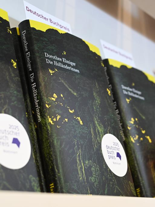 Eine Hand greift am Stand auf der Frankfurter Buchmesse nach dem Buch der Schweizer Autorin Dorothee Elmiger mit dem Titel "Die Holländerinnen".