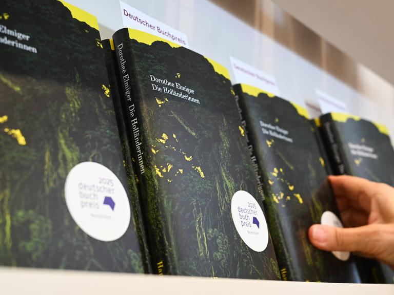 Eine Hand greift am Stand auf der Frankfurter Buchmesse nach dem Buch der Schweizer Autorin Dorothee Elmiger mit dem Titel "Die Holländerinnen".