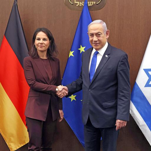 Israels Premierminister Benjamin Netanjahu begrüßt die deutsche Außenministerin Annalena Baerbock. Sie stehen vor Flaggen der EU, Deutschlands und Israel.
