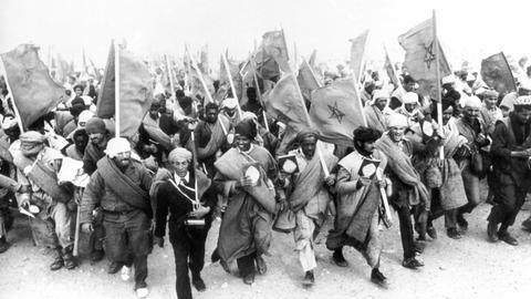 Ein Schwarz-Weiß-Foto zeigt Marokkaner, die mit marokkanischen Nationalflaggen marschieren.