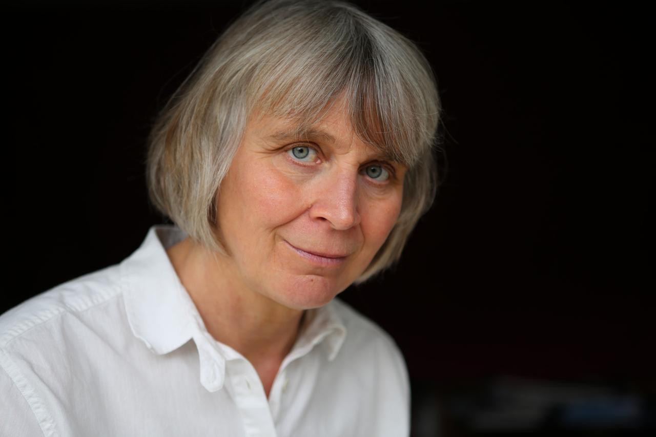 Porträt der Philosophin Barbara Schmitz. Sie trägt kutze, graue Haare und eine weiße Bluse vor schwarzem Hintergrund. Porträt der Philosophin Barbara Schmitz. Sie trägt kutze, graue Haare und eine weiße Bluse vor schwarzem Hintergrund.