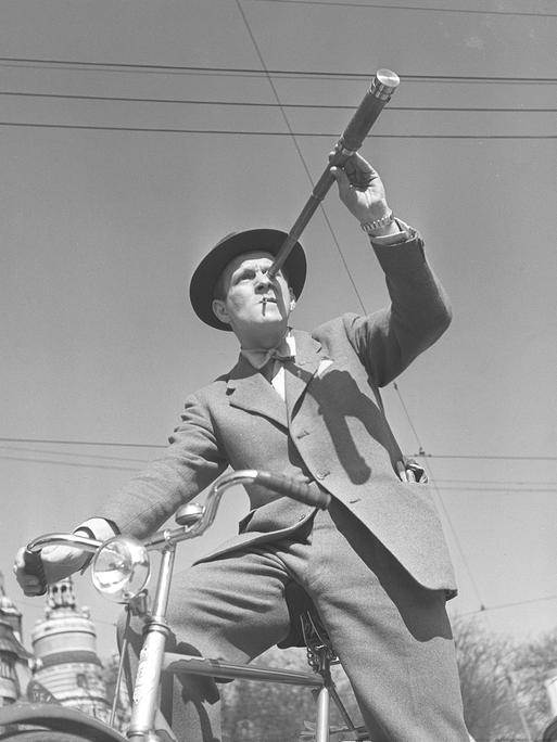 Schwarz-Weiß-Foto aus den1940er-Jahren: Ein Mann auf einem Fahrrad betrachtet etwas durch ein Fernrohr. 