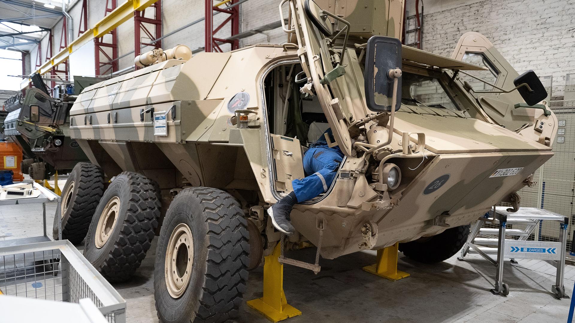 Ein Mitarbeiter von Rheinmetall arbeitet an einem Panzer vom Typ Fuchs in der Fertigungshalle von Rheinmetall. 