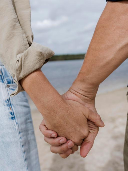 Ein Pärchen hält Händchen am Strand.