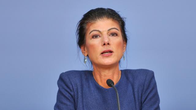 Sahra Wagenknecht sitzt bei einer Pressekonferenz in Berlin vor einem blauen Hintergrund.
