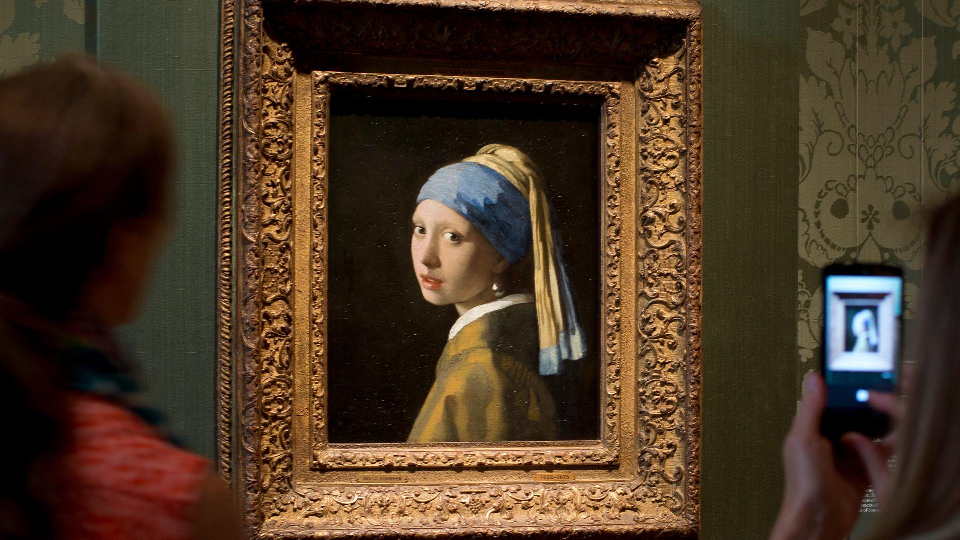 Besucher betrachten und fotografieren mit dem Handy das Gemälde "Das Mädchen mit dem Perlenohrring" von Johannes Vermeer im Mauritshuis-Museums in Den Haag. Besucher betrachten und fotografieren mit dem Handy das Gemälde "Das Mädchen mit dem Perlenohrring" von Johannes Vermeer im Mauritshuis-Museums in Den Haag.