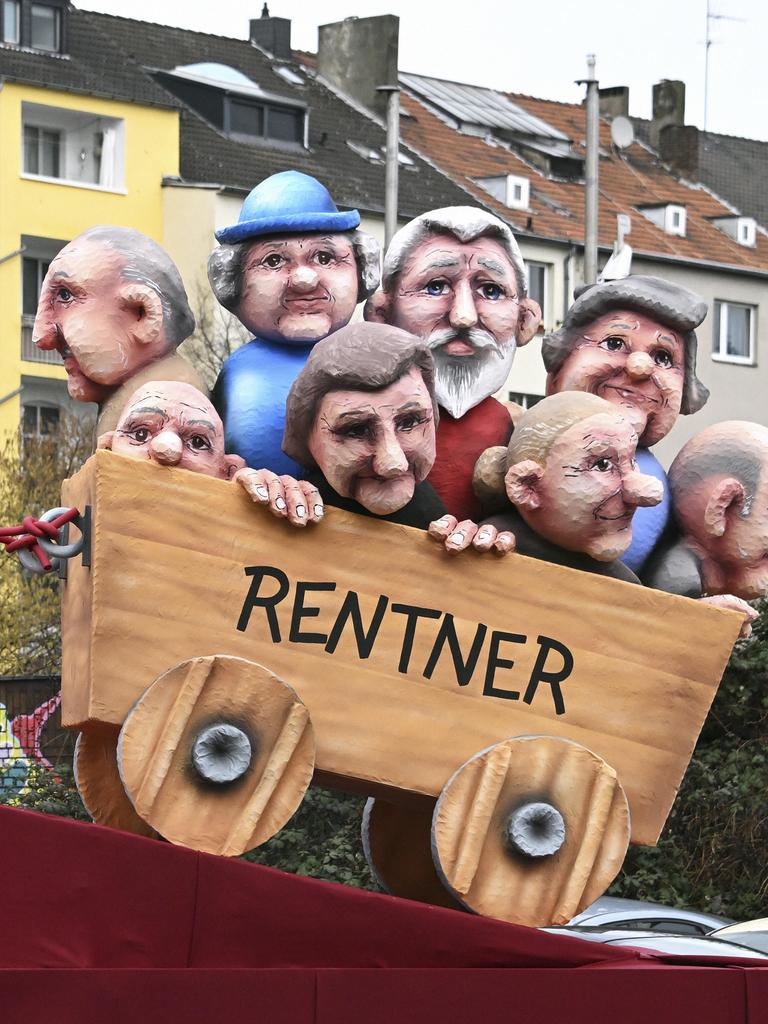 Rosenmontagszug in Düsseldorf: ein Themenwagen zeigt ein Baby, das mühevoll einen Karren mit Rentnern zieht.