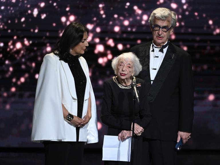 Die Holocaust-Überlebende Margot Friedländer spricht zwischen Menschenrechtsaktivistin, Düzen Tekkal (l), und Regisseur Wim Wenders (r) bei der Verleihung des Deutschen Filmpreises auf der Bühne. 