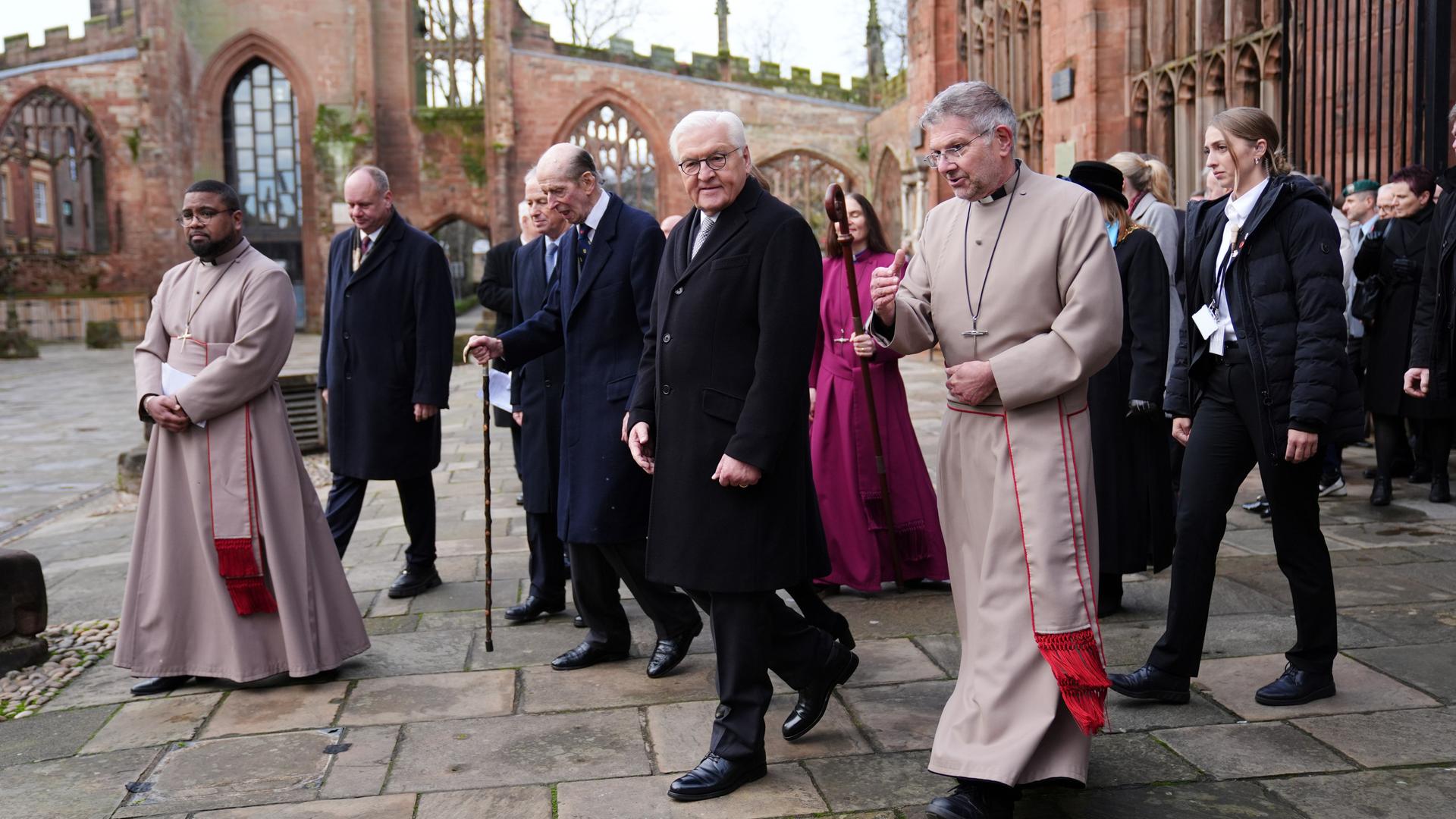 Bundespräsident Steinmeier und seine Frau kommen in Coventry an. Sie werden von mehreren Kirchenleuten und der Presse begleitet.